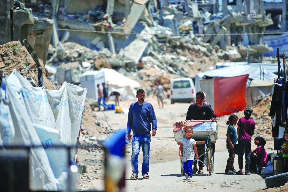 Palestinians walk near rubble of houses in Jabalia refugee camp, in the northern Gaza Strip,  yesterday