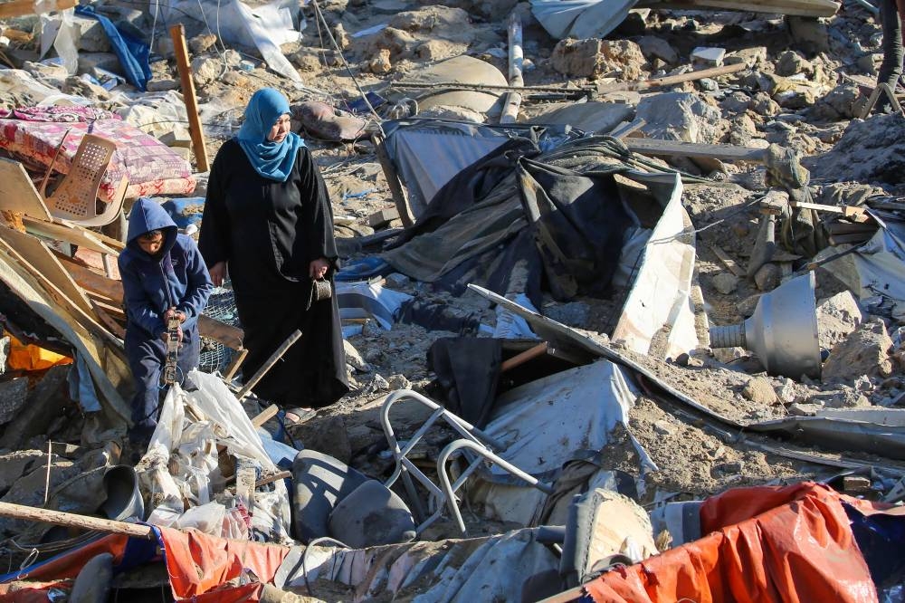 Palestinians sift through destroyed shelters at a UNRWA school housing displaced people, following an Israeli strike in the Bureij refugee camp in the centre of the Gaza Strip.