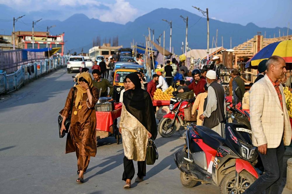 Locals walk past vendors along a roadside in Srinagar on Saturday. AFP