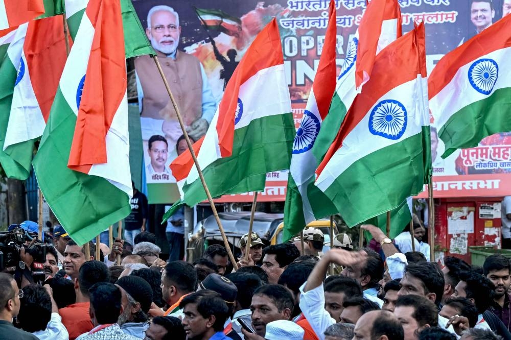 Activists hold the national flag of India in front a banner that praises the Indian defence forces for their military operation, code-named "Operation Sindoor", in Mumbai on Saturday. AFP
