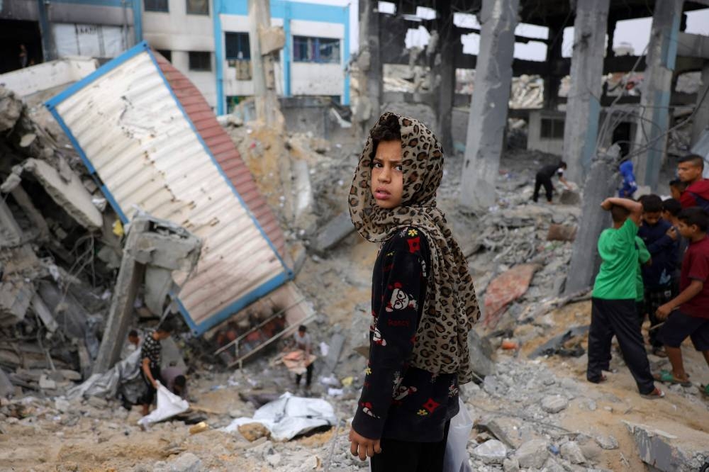 A young Palestinian girl looks on as children gather amid the rubble of an UNRWA school-turned-shelter, heavily damaged in an overnight Israeli strike in Jabalia in the northern Gaza Strip on Saturday. AFP