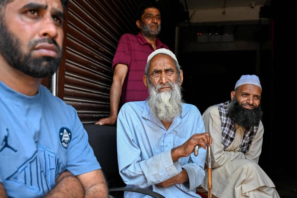 Shop owners look on as they sit in the market near a bus station in the main town of Poonch district in Jammu regio, on Sunday. AFP