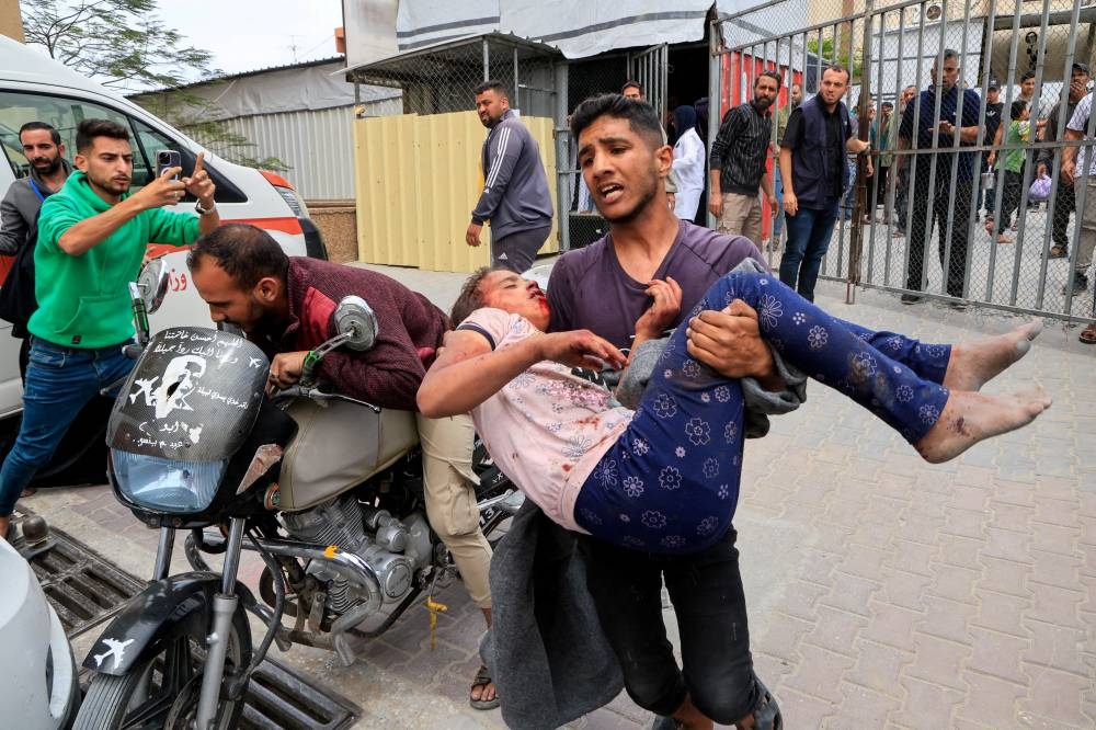 Palestinian man carries a wounded person to Nasser hospital following an Israeli strike, in Khan Younis, southern Gaza Strip, on Thursday. REUTERS