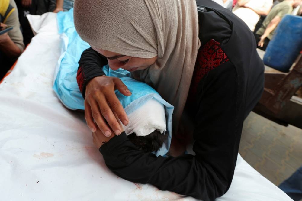 A mourner embraces the body of a Palestinian child killed in an Israeli strike, at Al-Aqsa Martyrs hospital, in Deir Al-Balah in the central Gaza Strip, on Sunday. REUTERS