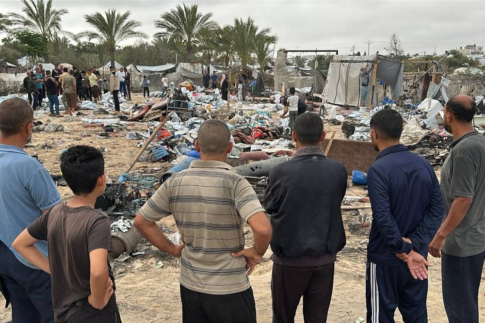 Palestinians inspect the debris at the site of Israeli strikes on a displacement tent camp, in the Mawasi area west of Khan Yunis in the southern Gaza Strip, on Sunday. AFP