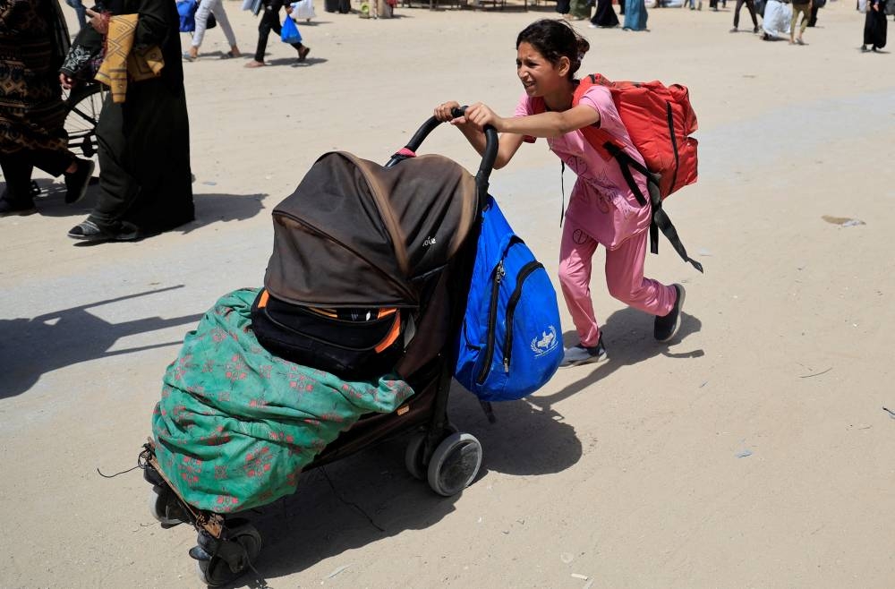 A girl pushes a stroller with belongings as Palestinians flee their homes after the Israeli military issued orders for evacuation from eastern Khan Younis, in the southern Gaza Strip on Monday. REUTERS
