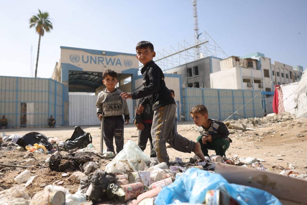 Palestinian children play near the UN agency for Palestinian refugees UNRWA headquarters gate in Gaza City, on Tuesday. AFP