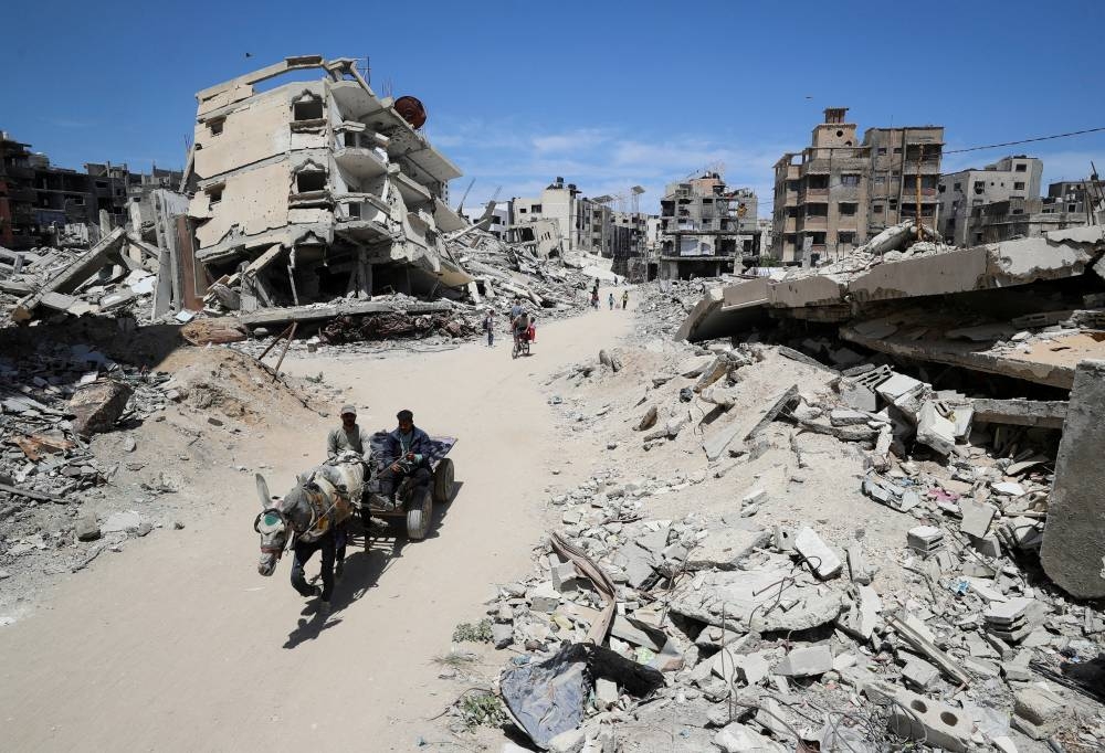 Palestinians ride a cart past the rubble of houses, in Gaza City, on Tuesday. REUTERS