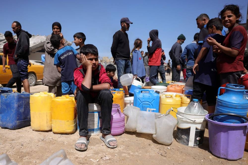Palestinians attempt to collect water at a camp for displaced people in Gaza City, on Tuesday. AFP