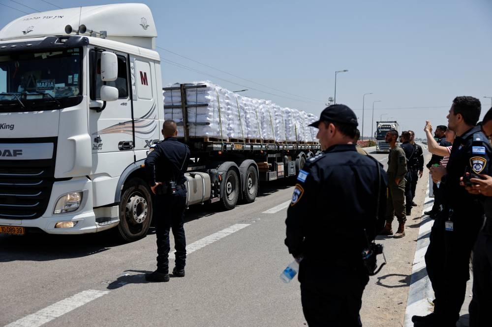 Israeli security forces members stand near trucks with aid entering from Israel into Gaza, near the Kerem Shalom crossing near the Israeli border with Gaza on Wednesday. REUTERS