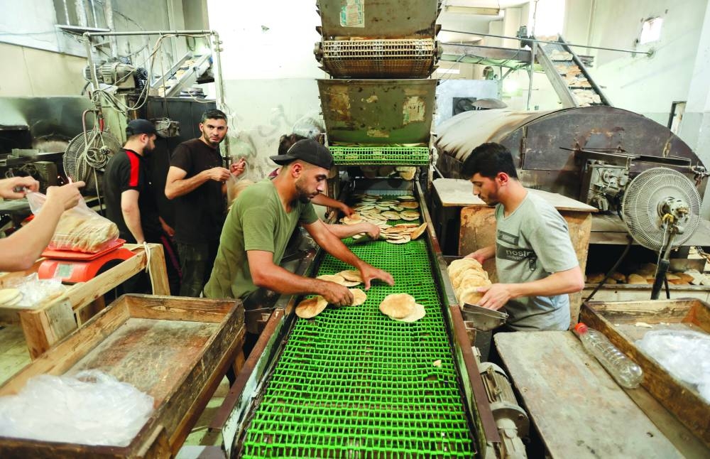 
Palestinian workers make bread in a bakery that returned to operation in Deir Al-Balah, in the central Gaza Strip, yesterday. 