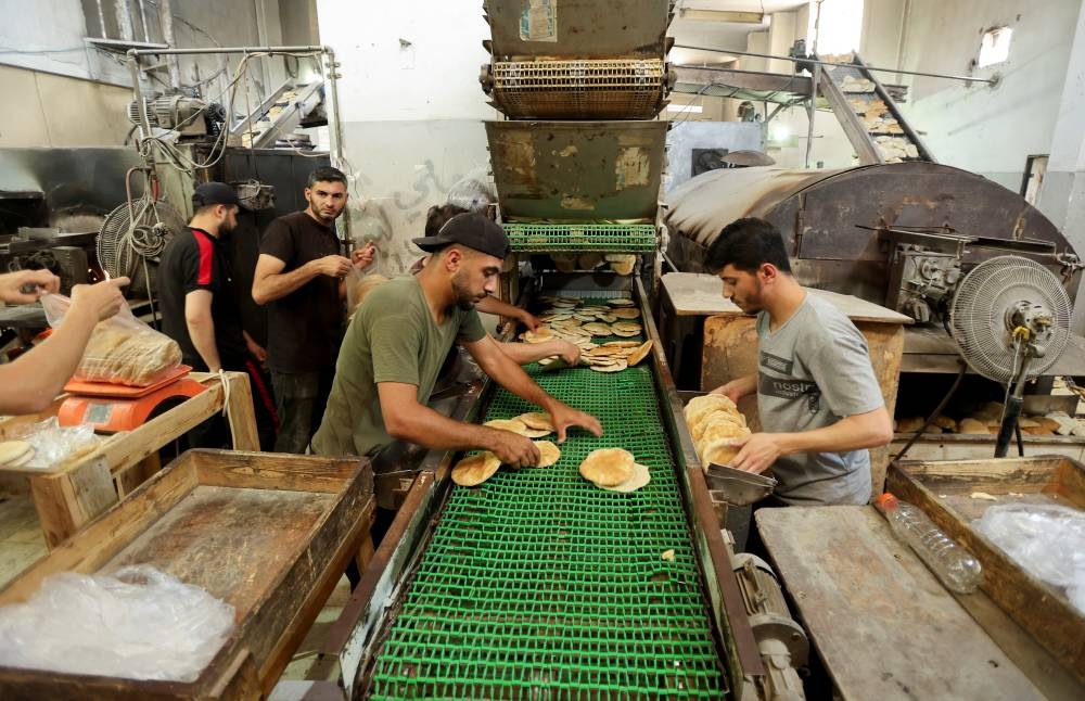 Palestinian workers make bread in a bakery that returned to operation  in Deir Al-Balah, in the central Gaza Strip, yesterday