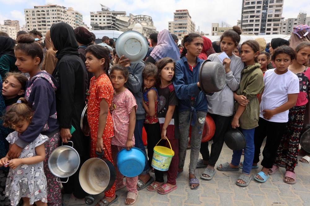 Palestinians, most of them children, queue in front of a hot meal distribution truck, at a displacement camp near Gaza City's port on, on Thursday. AFP