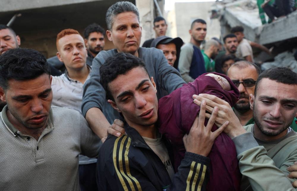 Palestinians carry the body of an infant at the site of an Israeli strike on a house, in Jabalia, northern Gaza Strip, on Friday. REUTERS