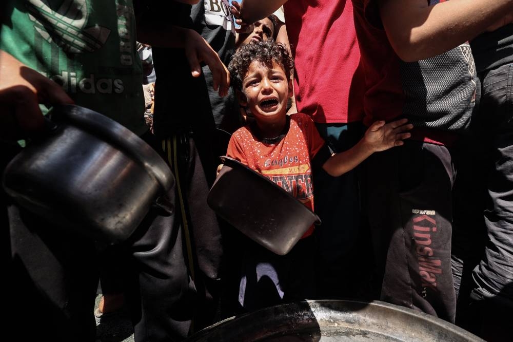 A child cries as Palestinians gather to receive a hot meal at a food distribution point in the Nuseirat camp for refugees in the central Gaza Strip on on Saturday. AFP