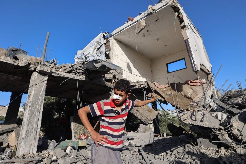 A Palestinian boy stands outside a destroyed house that was targeted in an Israeli strike at the Nuseirat camp for refugees in the central Gaza Strip on Saturday. AFP