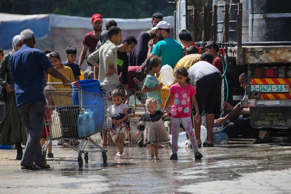 Palestinians gather to fill their containers with water in the Nuseirat camp for refugees in the central Gaza Strip on Saturday. AFP