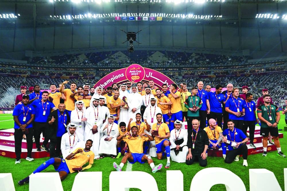 Al Gharafa players, support staff and officials celebrate with the trophy after the their Amir Cup triumph at the Khalifa International Stadium Saturday.