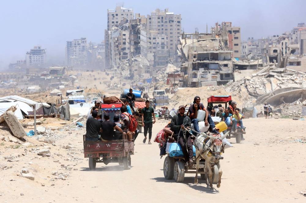 Palestinians transport their belongings as they flee the northern Gaza Strip toward the south, along the coastal al-Rashid road, on Sunday. AFP