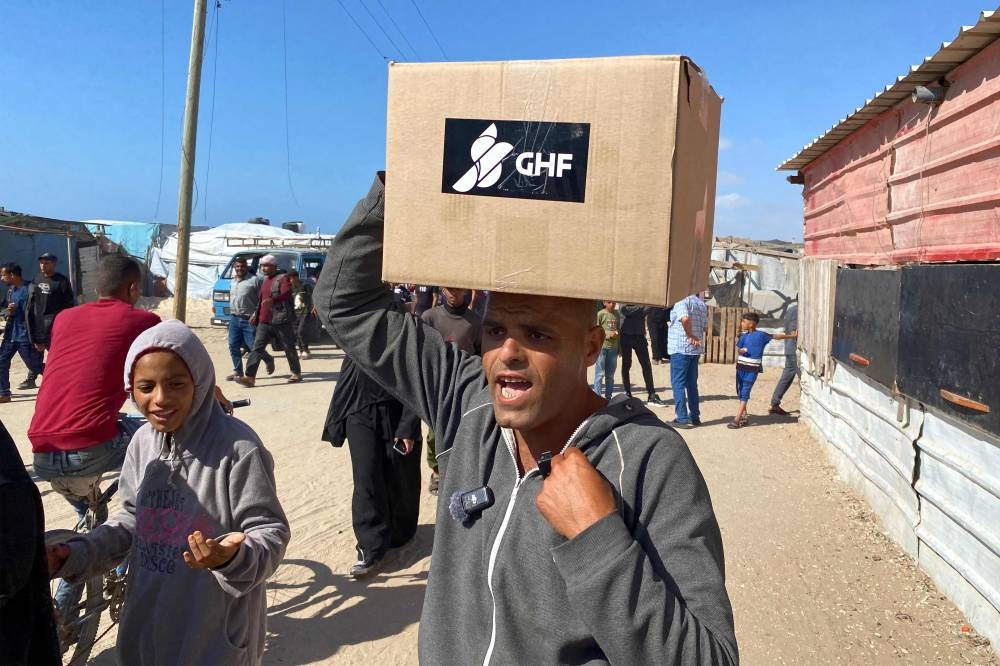 Displaced Palestinians receive food packages in western Rafah Tuesday.
