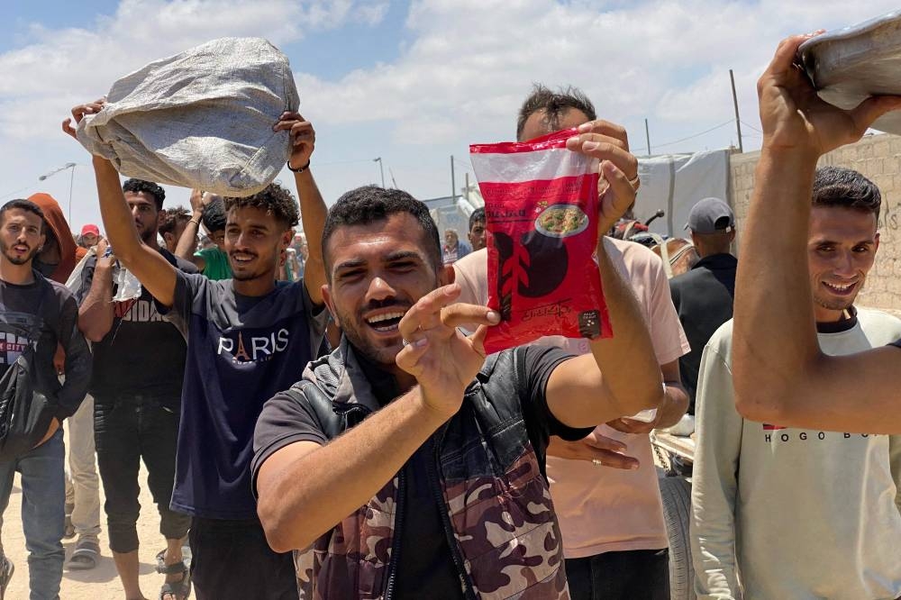 Displaced Palestinians react as they display items received from an aid distribution center in Khan Yunis in the southern Gaza Strip, on Wednesday. AFP
