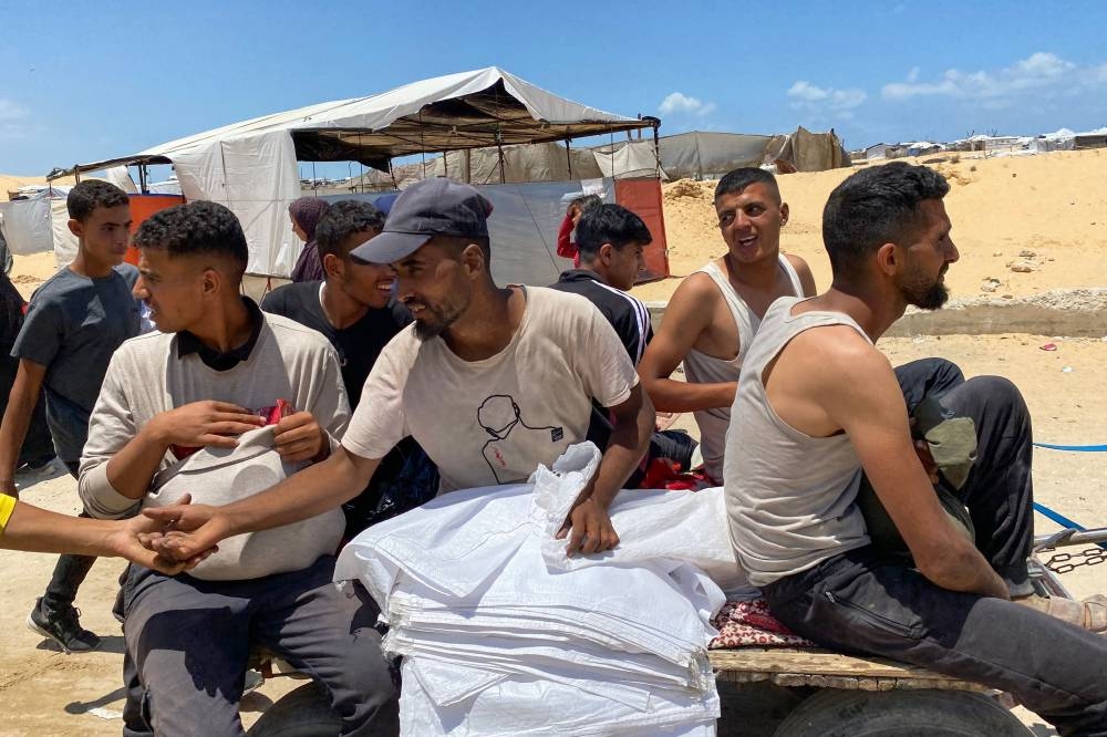 Displaced Palestinians, some carrying a bag of foodstuffs, sit on a cart as they return from an aid distribution center in Khan Yunis in the southern Gaza Strip, on Wednesday. AFP