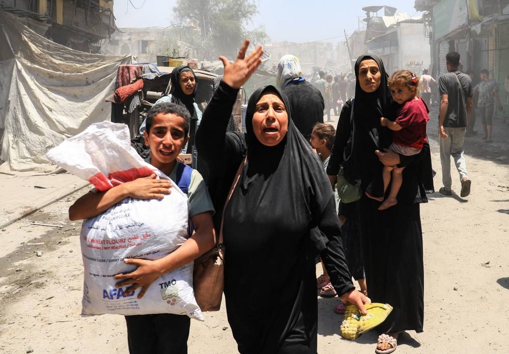 Palestinians evacuate in the aftermath of an Israeli strike on a house in Gaza City on Friday.