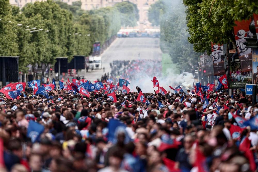 Paris Saint-Germain's supporters wave as they wait for the team bus to parade on the Champs-Elysees avenue in Paris on Sunday. AFP