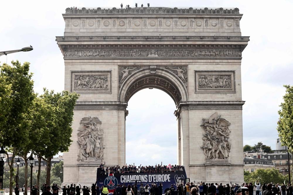 Paris Saint-Germain's team players and staff celebrate in front of the Arc de Triomphe monument during the bus parade on the Champs-Elysees avenue in Paris on on Sunday. AFP