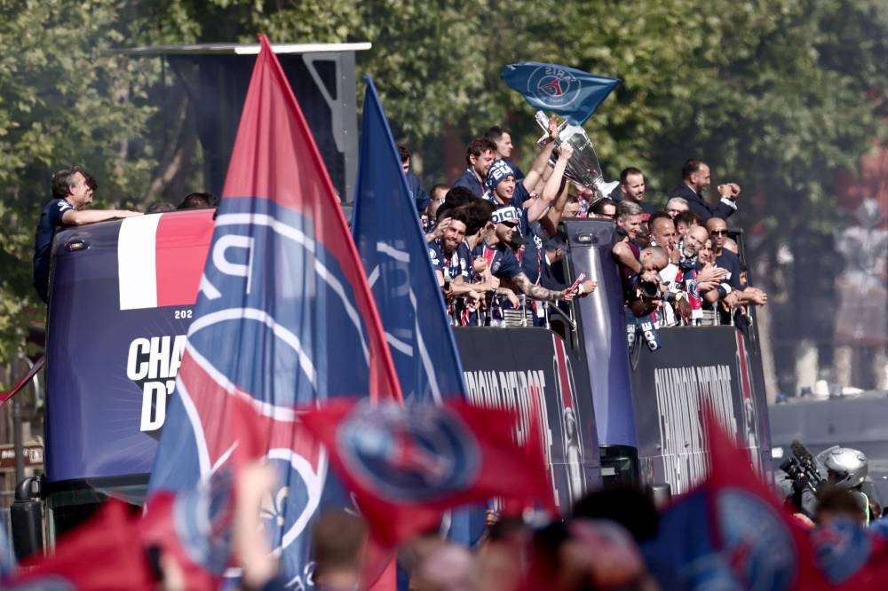 Paris Saint-Germain's supporters wave as the PSG team bus parades on the Champs-Elysees avenue in Paris on Sunday. AFP