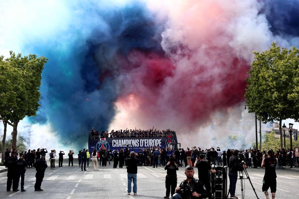 Smoke flares explode as the PSG team bus parades on the Rond Point de L'Etoile in front of the Arc de Triomphe in Paris on on Sunday. AFP