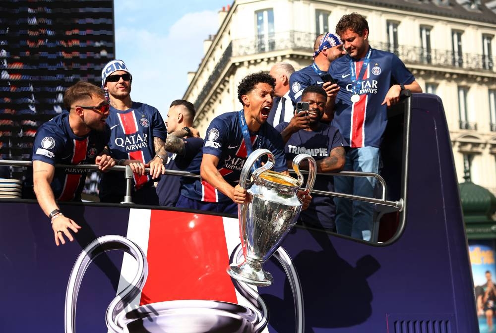 Paris St Germain's Marquinhos celebrates with the trophy and teammates after winning the Champions League on the bus during the victory parade. REUTERS