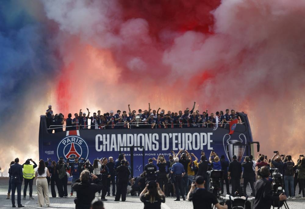 General view of smoke rising as the Paris St Germain players celebrate after winning the Champions League on the bus during the victory parade. REUTERS