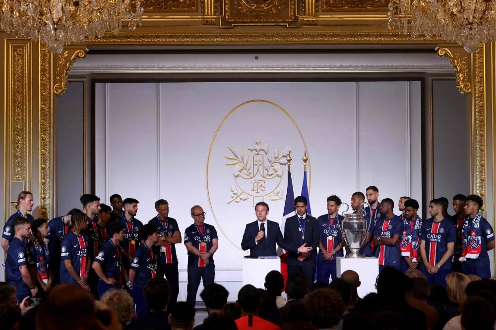 France's President Emmanuel Macron (C) delivers a speech next to Paris Saint Germain team's players and staff, as the trophy is displayed on stage, during the reception at the Elysee presidential palace in Paris on Sunday. AFP