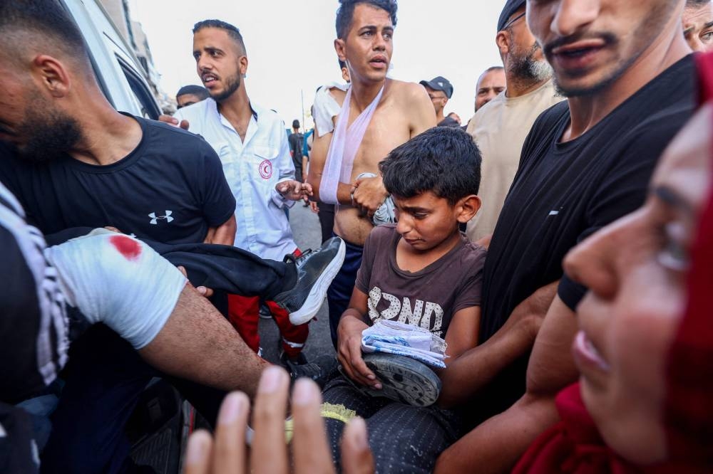 Palestinian rescuers evacuate injured people in an ambulance after an Israeli drone reportedly opened fire on civilian gatherings near an aid distribution point in the central Gaza Strip, on Sunday, at Bureij camp. AFP