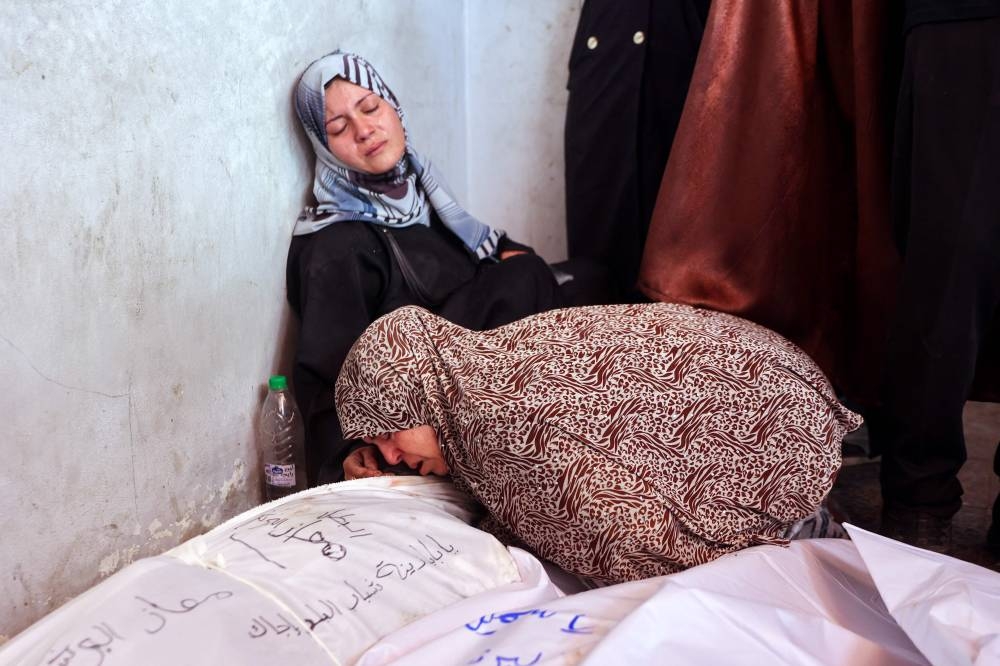 Palestinians mourn over the shrouded body of a loved one, who was killed during an Israeli strike that targeted the home of the al-Bursh family in Jabalia in the northern Gaza Strip, on Monday. AFP