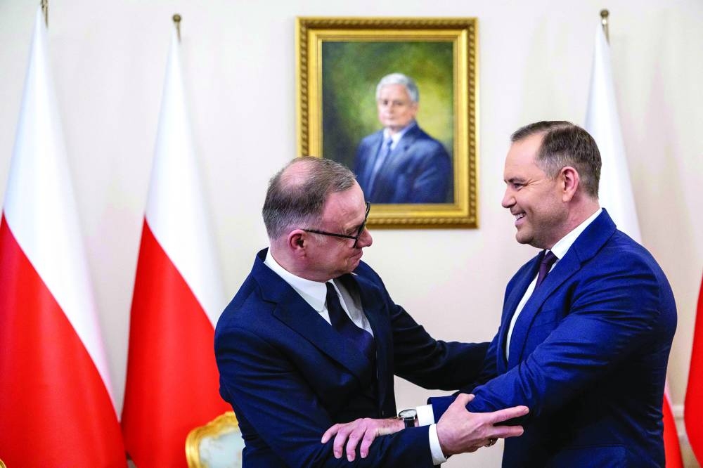 
President-elect Karol Nawrocki (right) and President Andrzej Duda embrace in front of a portrait of late former president Lech Kaczynski at the Presidential Palace in Warsaw last Tuesday. (AFP) 