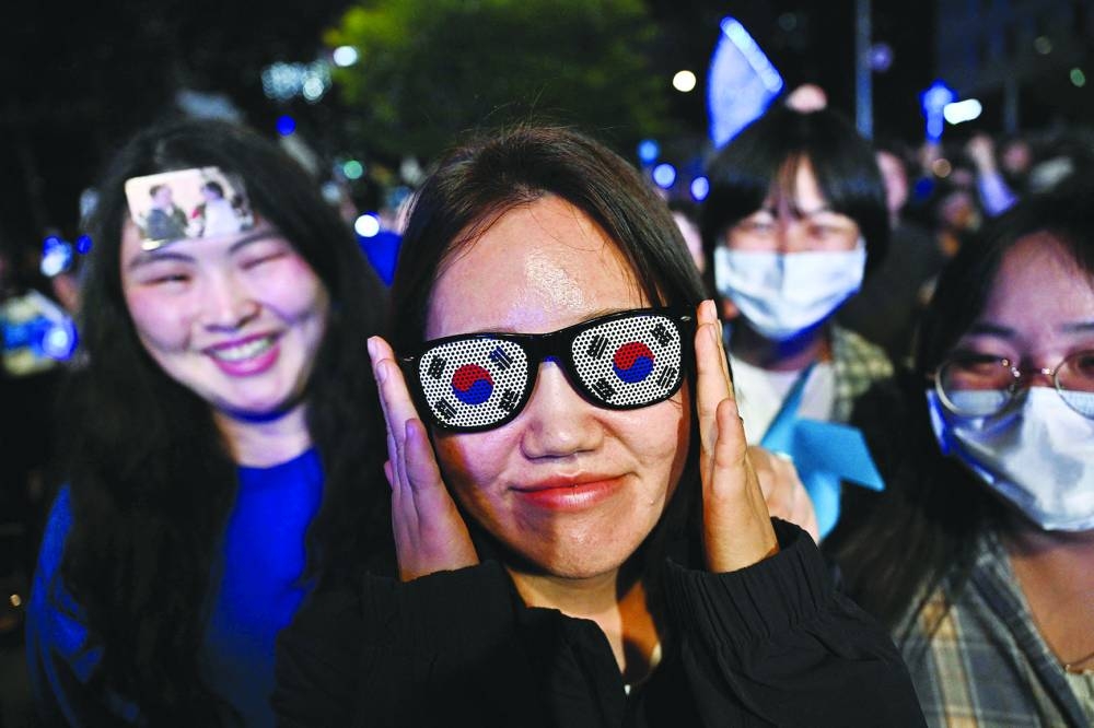 
Supporters of Lee Jae-myung shout slogans with one wearing sunglasses adorned with the national flag in Seoul. (AFP) 