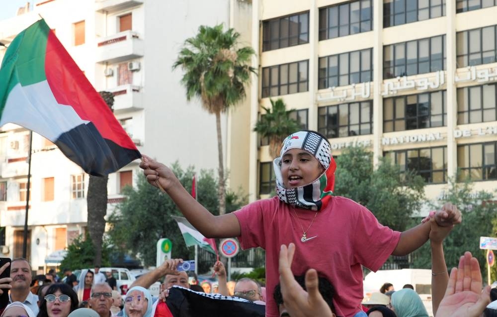 A child holds a Palestinian flag, as participants of a Tunisian-led land convoy, who aim to reach Gaza and call for an end to the conflict in the region, gather before they board buses, in Tunis, on Monday. REUTERS