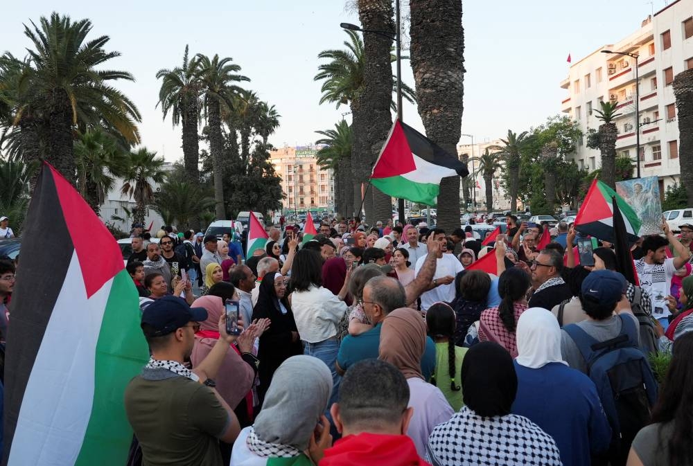 People hold Palestinian flags, as participants of a Tunisian-led land convoy, who aim to reach Gaza and call for an end to the conflict in the region, gather before they board buses, in Tunis, on Monday. REUTERS
