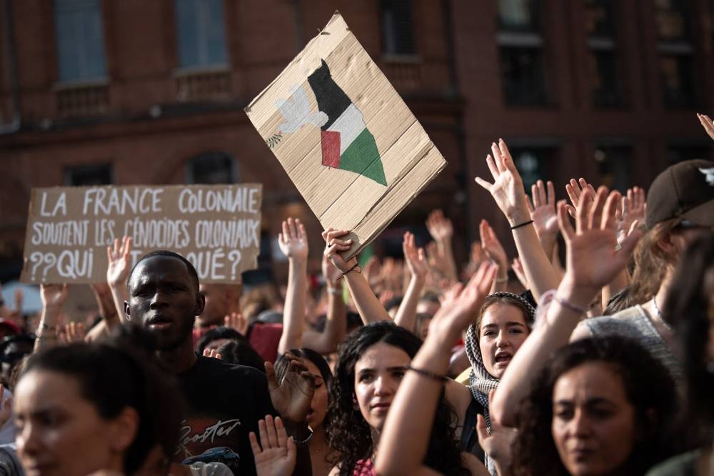 Protestors hold signs reading "Colonial France supports colonial genocide" (L) as they attend a demonstration to show their support for activists aboard a boat stopped by Israeli forces enroute to deliver aid to Gaza, in Toulouse, south-western France on Monday. AFP