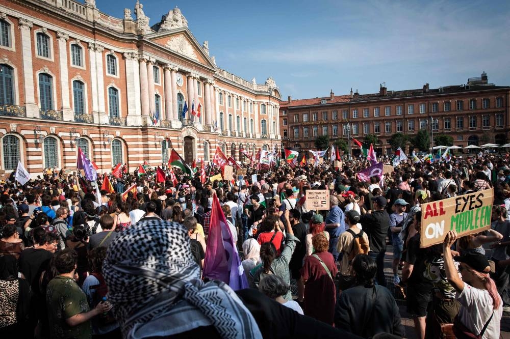 Protestors hold signs reading "Neutrality = complicity" (C) and Palestinian flags as they attend a demonstration to show their support for activists aboard a boat stopped by Israeli forces enroute to deliver aid to Gaza, in Toulouse, south-western France on Monday. AFP