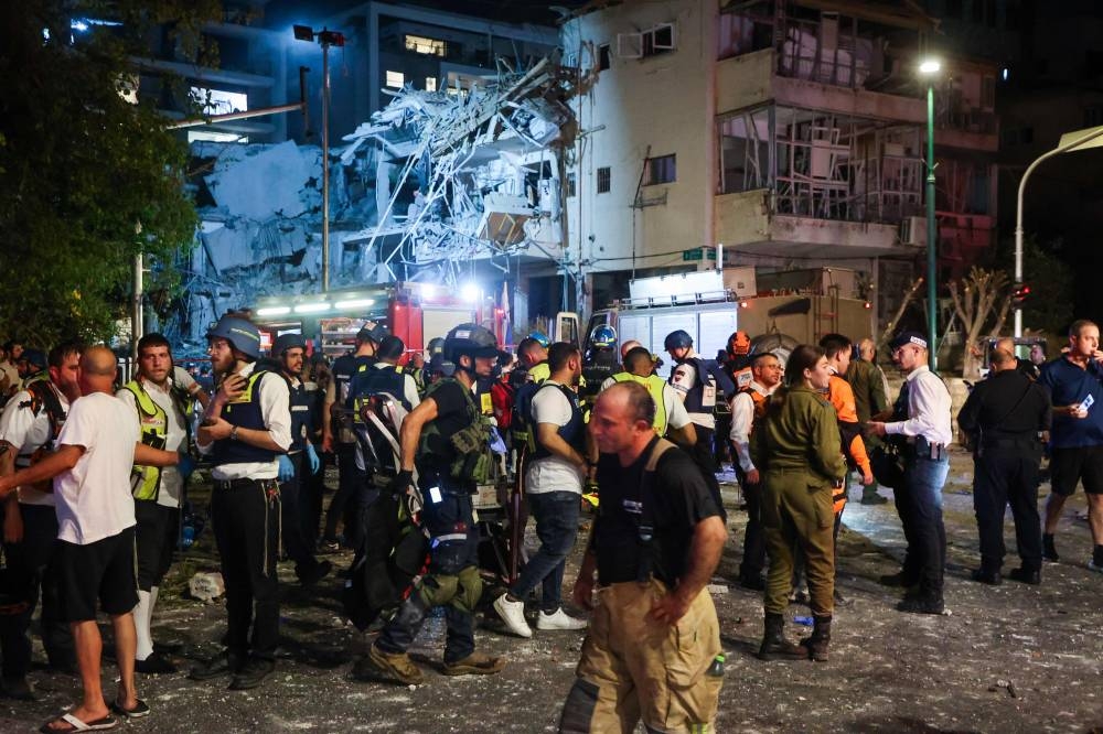 Israeli first responders arrive at a site hit by a missile fired from Iran, in Ramat Gan on the outskirts of Tel Aviv on Friday. AFP