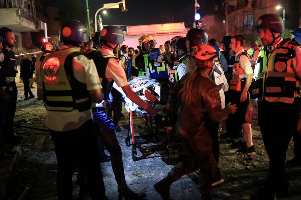 Rescue and security personnel carry a wounded person at an impact site following missile attack from Iran on Israel, in  Ramat Gan, Israel on Friday. REUTERS