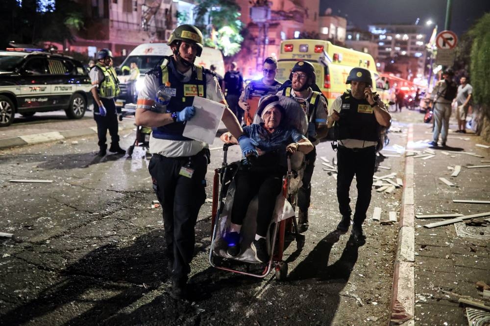 Rescue personnel evacuate a wounded woman at an impact site following missile attack from Iran on Israel, in Ramat Gan, Israel on Friday. REUTERS