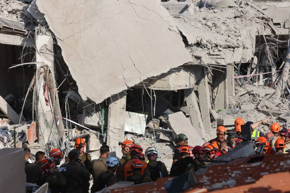 Israeli emergency responders inspect a site hit by a missile fired from Iran near Tel Aviv , on Saturday. AFP