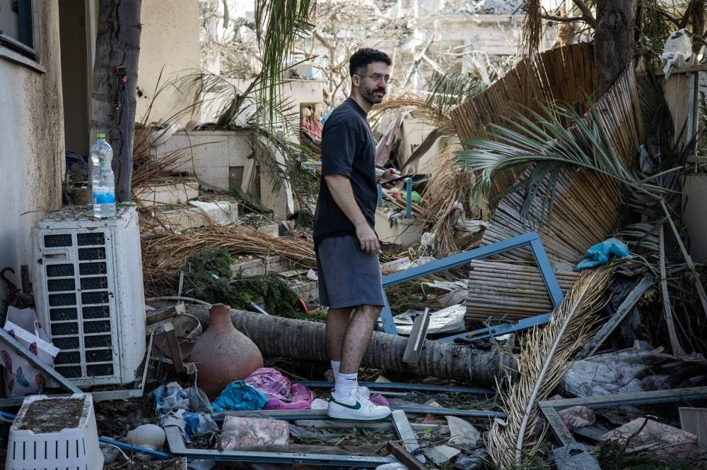 A man inspects the debris at a site hit by a missile fired from Iran south of Tel Aviv on  Saturday. AFP