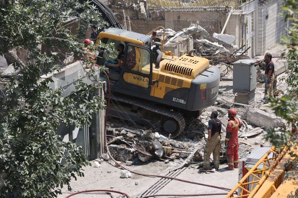 Rescuers work at the site of a damaged building, in the aftermath of Israeli strikes, in Tehran, Iran, on Saturday. REUTERS