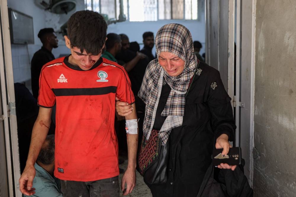 A woman and boy react as they mourn a person killed following reported Israeli attacks on aid queues in the Sudaniya area in northwestern Gaza, at Al-Shifa hospital in Gaza City on Saturday. AFP