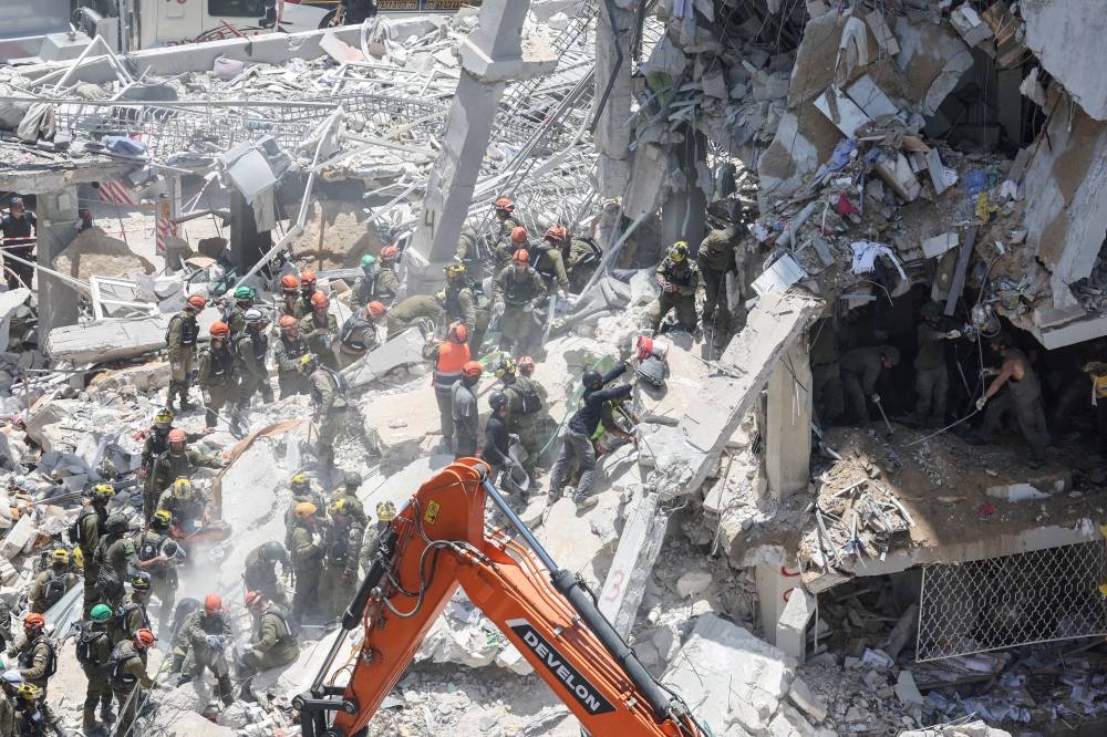 Rescue personnel work at an impact site following a missile attack from Iran, in Bat Yam, Israel, on Sunday. REUTERS